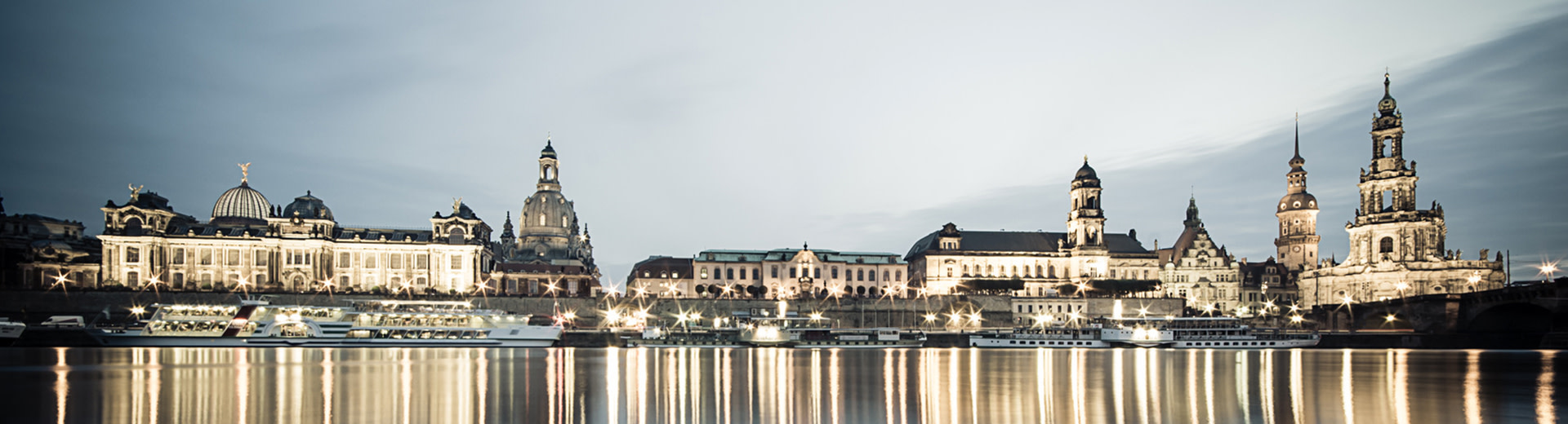 The main square in Dresden is lit up at night under a black sky.