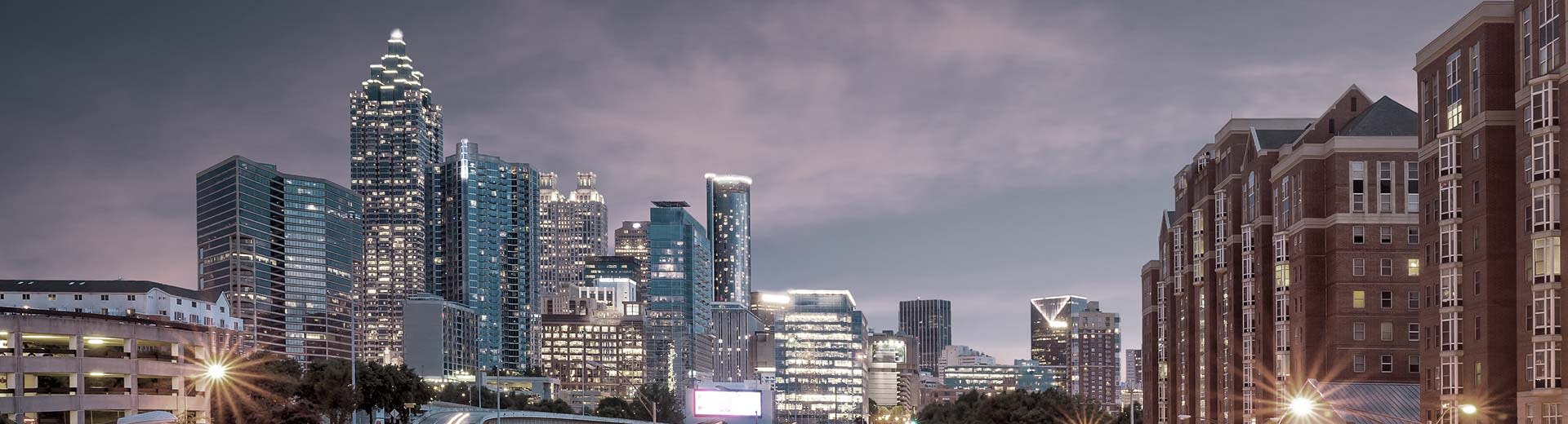 Image de la ligne d'horizon de la ville d'Atlanta dans la soirée, avec les lumières du bâtiment créant une lueur.