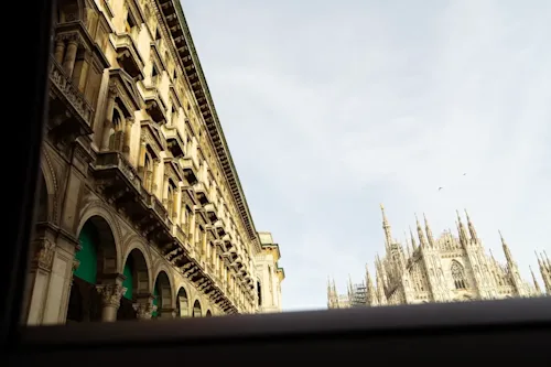 Shot of the spires of the cathedral in Milan and a building on the piazza through the sunroof of a luxury car.