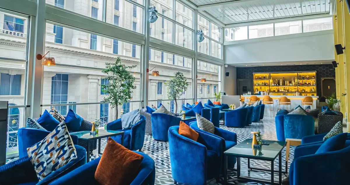 Shot of the Olival terrace in Neera Dubai private members' clubs, showing comfy seating and a bar in the background.