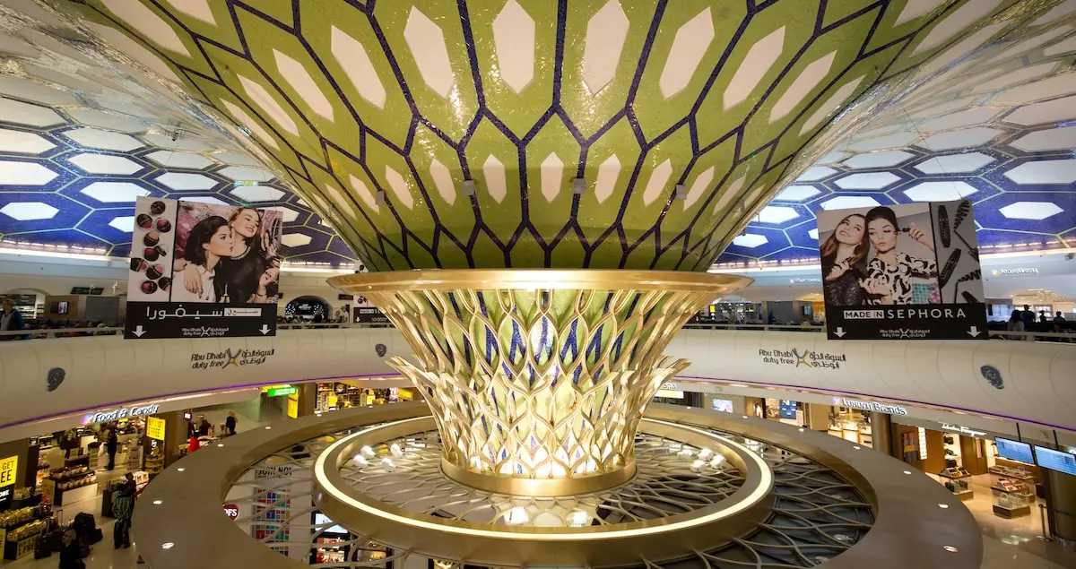 A shot of the terminal interior of Abu Dhabi Airport showing the ornate roof and ads for Sephora shops.