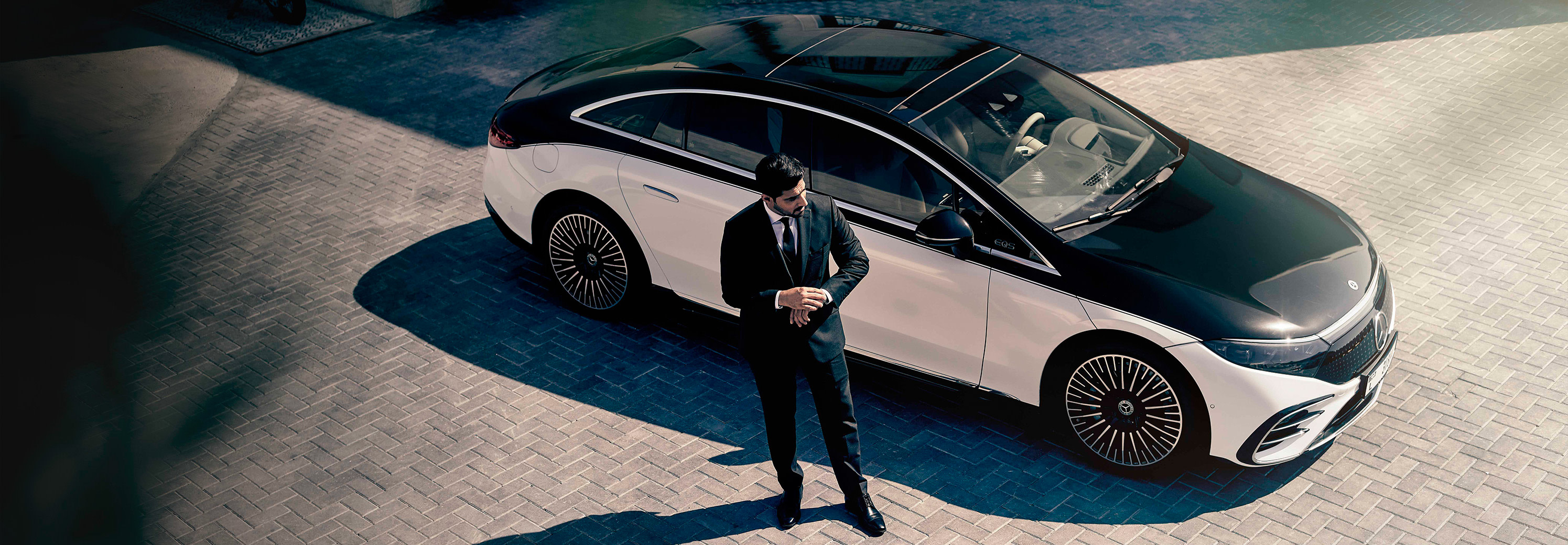 A Blacklane chauffeur standing outside a brand-new Mercedes-Benz EQS.
