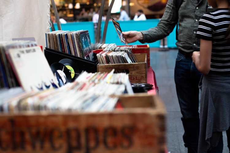 A man selecting a vinyl record out of a box of records | A man selecting a vinyl record out of a box of records