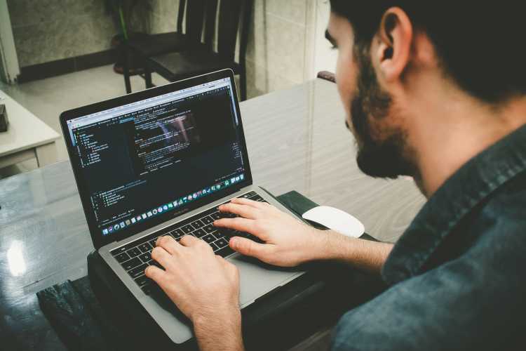 Man with beard coding on MacBook Pro