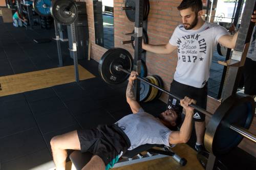 personal trainer helping client with weight lifting