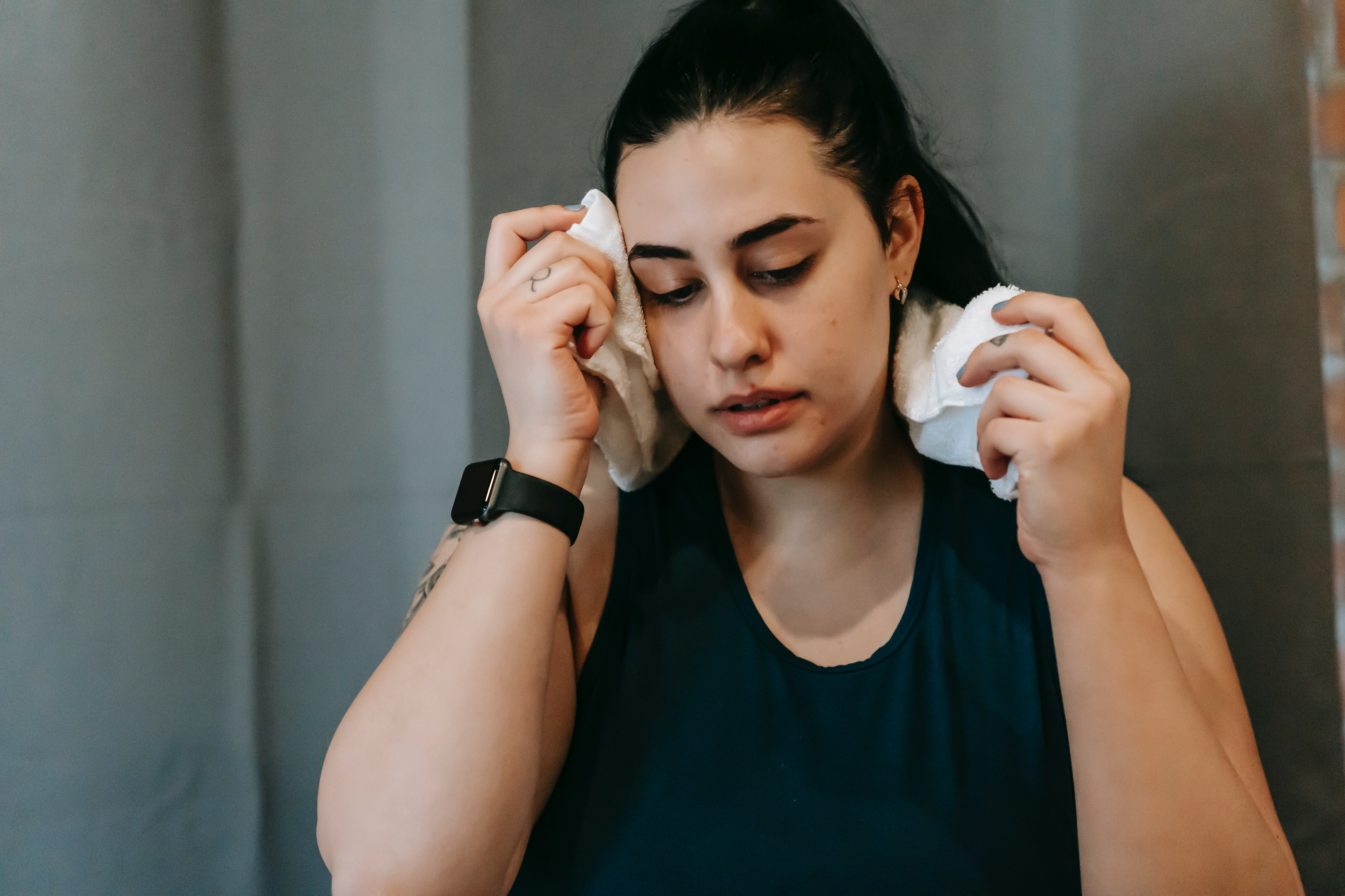 Woman wiping head with gym towel