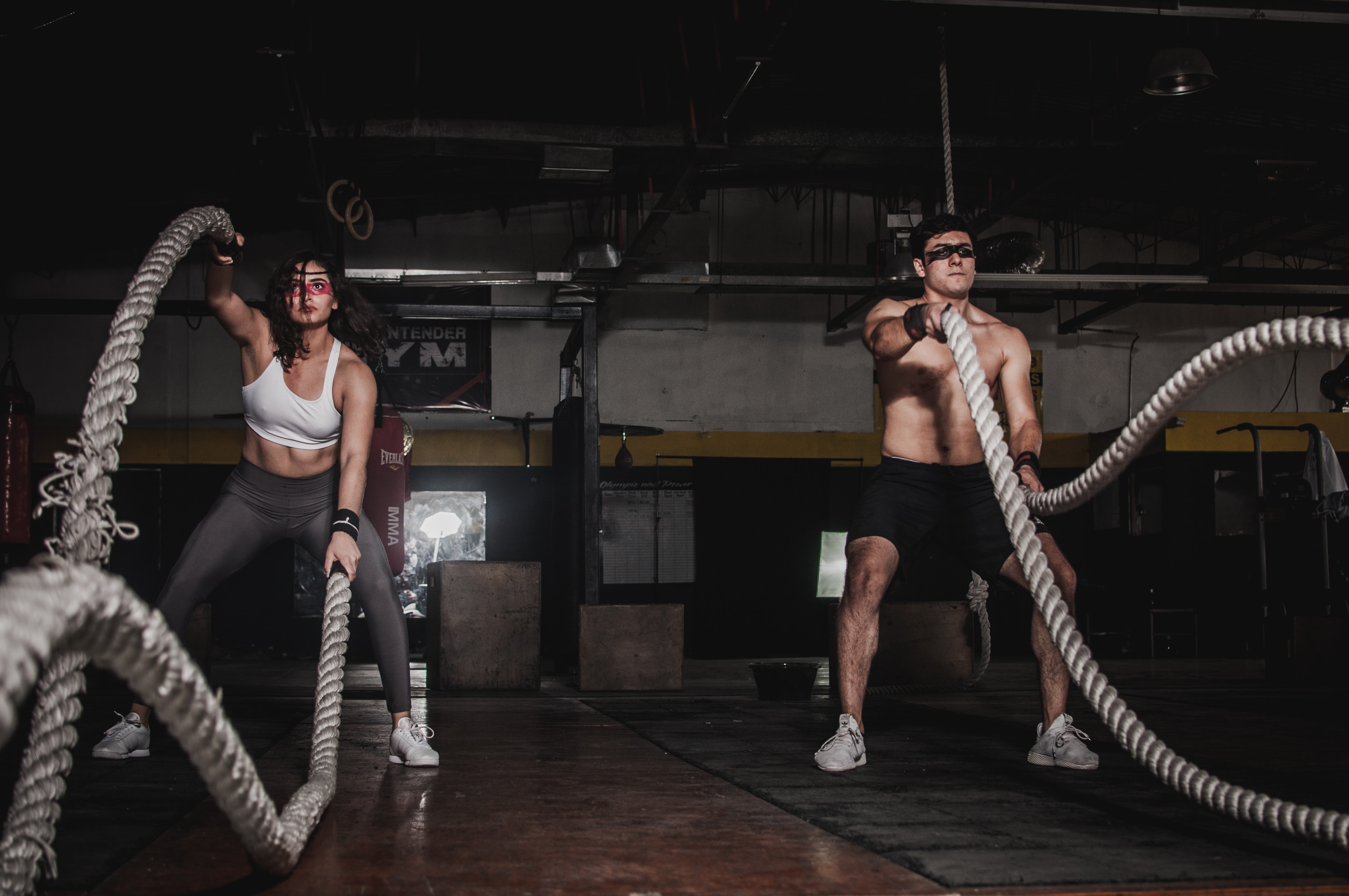 Man and women in the gym exercising using rope equipment