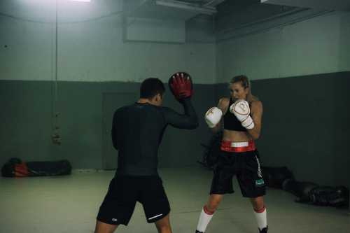 Personal trainer holding the pads while client hits them with boxing gloves on