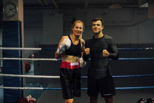Client proudly standing with personal trainer in boxing attire