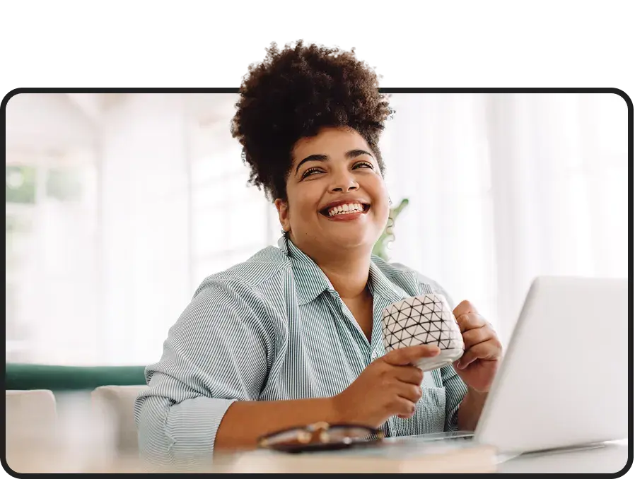 Woman smiling while holding a mug at a table