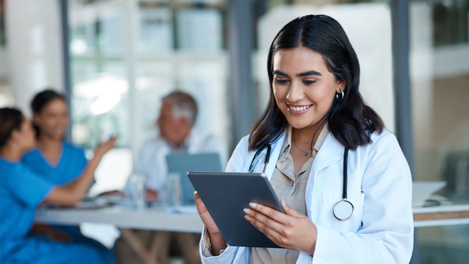 A female doctor reviewing patient information on a tablet in a clinic.