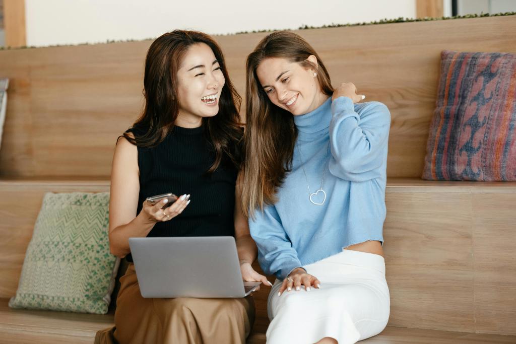 Two women having a fun conversation in front of their laptop