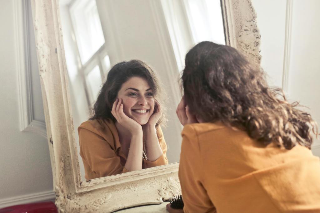 A happy woman looking into a mirror