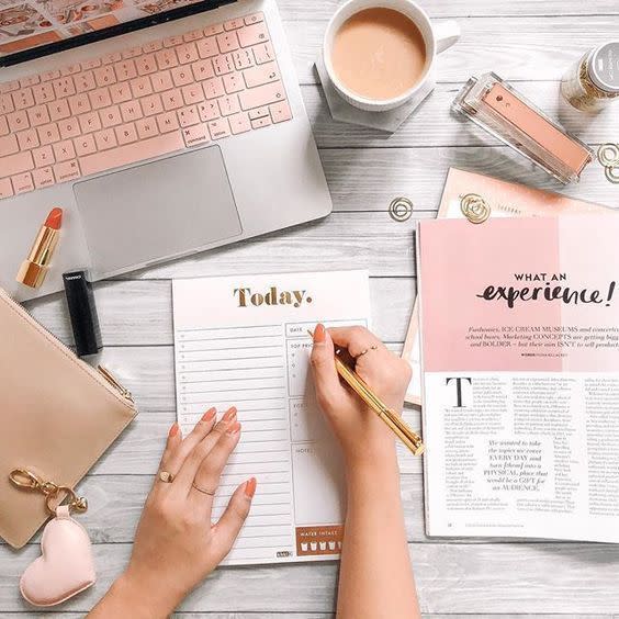 A person writing on their notebook beside various stationery items