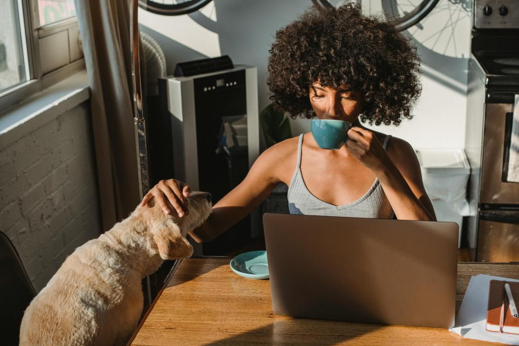 A woman sipping coffee while petting her dog