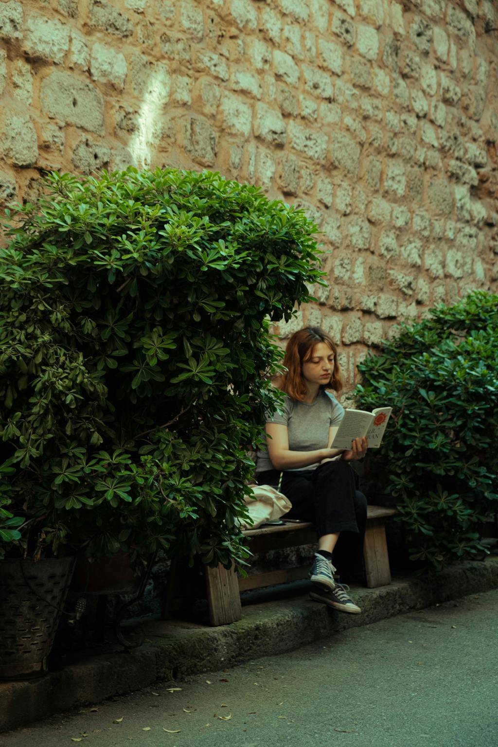 A woman sitting in a garden while reading a book