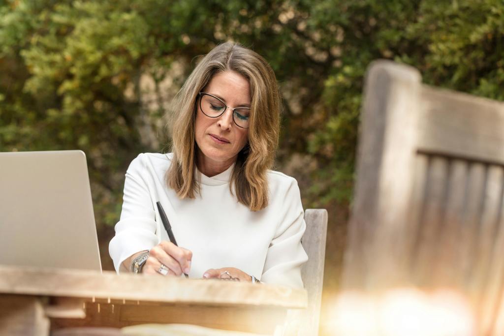 A woman writing on her notebook in an outside setting