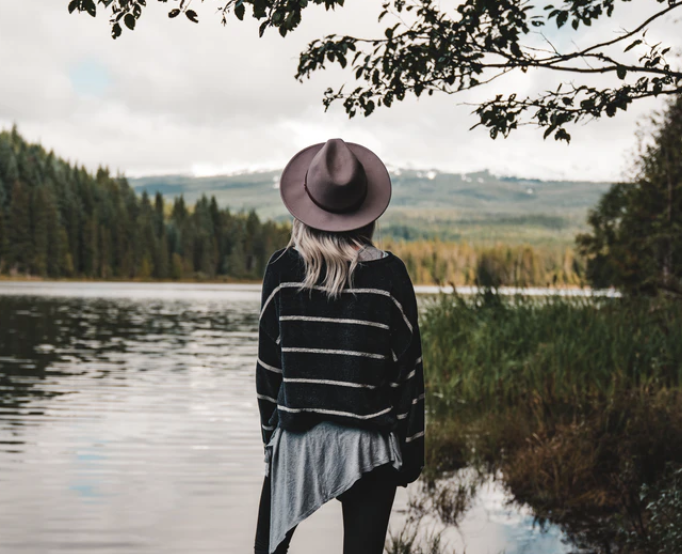 A woman facing towards a beautiful lake