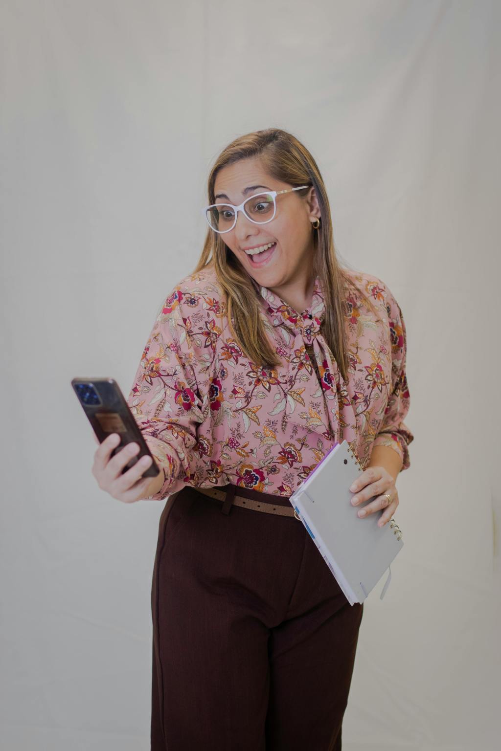 A woman looking at her phone with a shocked, but happy expession on her face