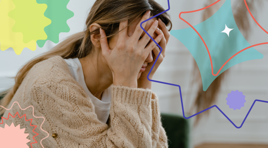 A seemingly stressed woman sitting down with her palms on her face