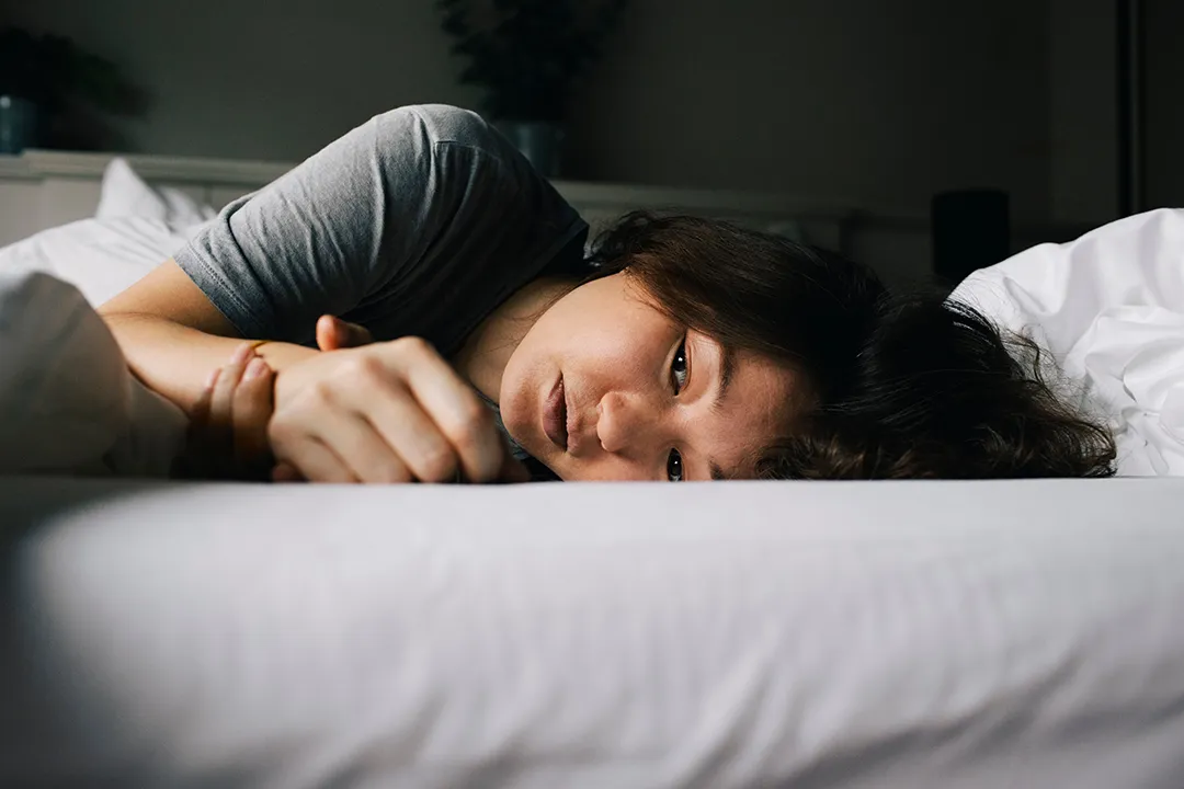 Depressed Woman Lying On Side In Bed