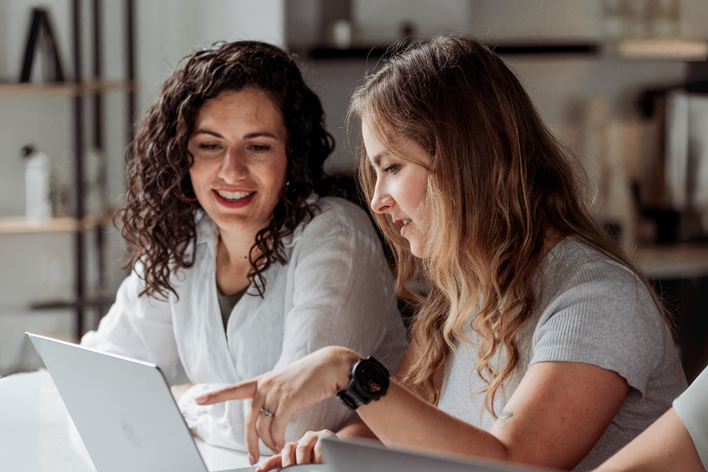 two women looking at one laptop