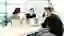a group of people sitting around a table in an office, working