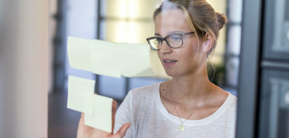 An Employee places a Post-it on a glass wall.