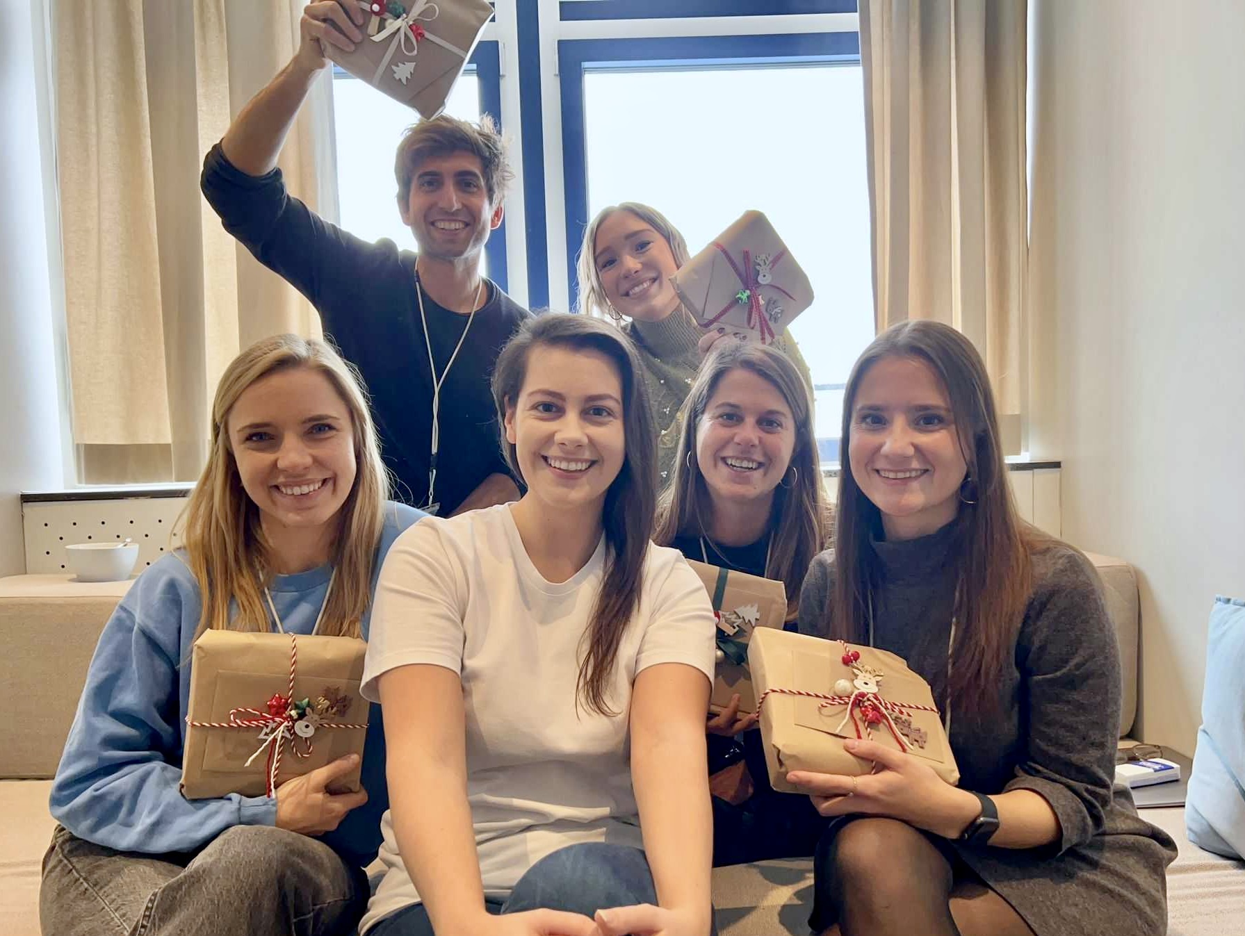 Maria Gotz with 5 teammates holding holiday gifts