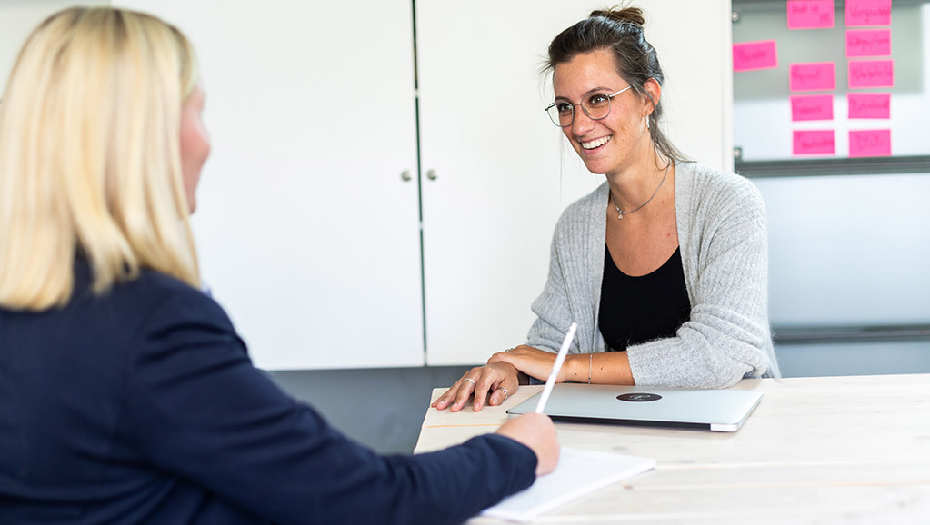 two woman sitting across each other in an office