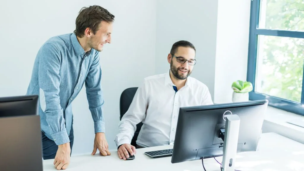 Two employees are looking at a computer