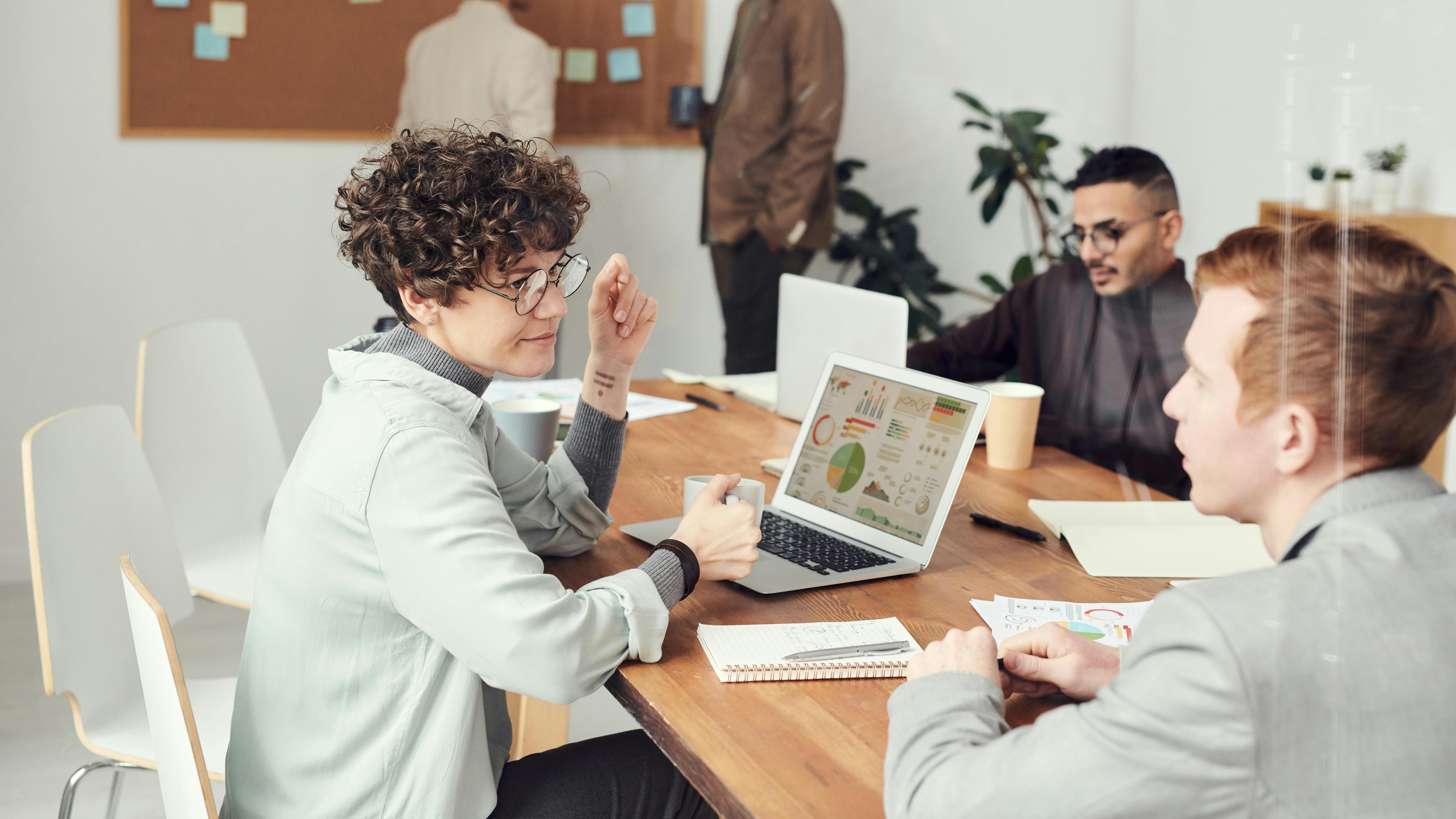 Drie mensen in een werksessie met een laptop waarop grafieken en diagrammen worden weergegeven.