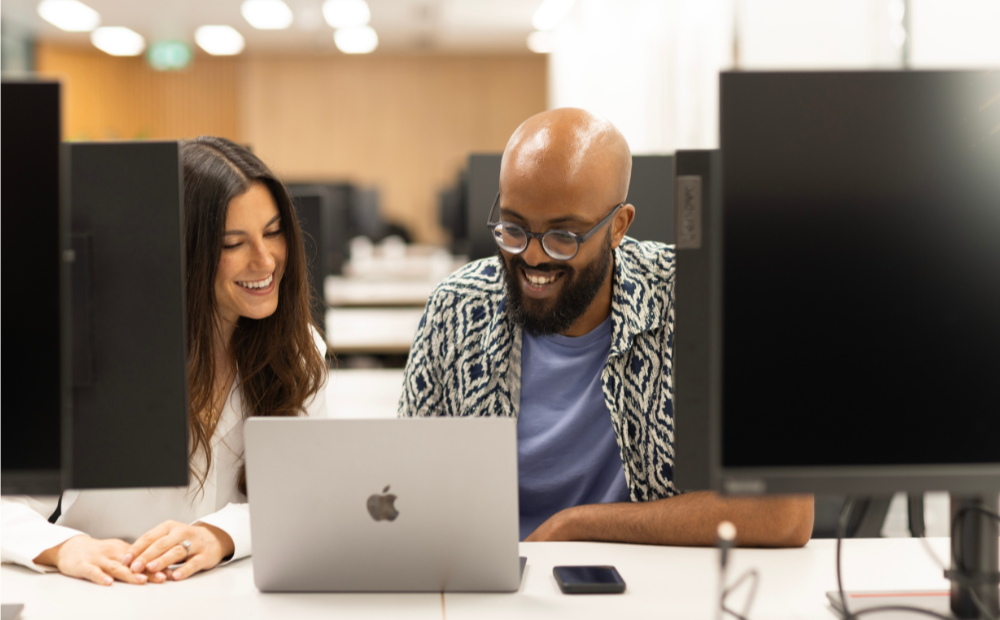 woman and man laughing at laptop on london office