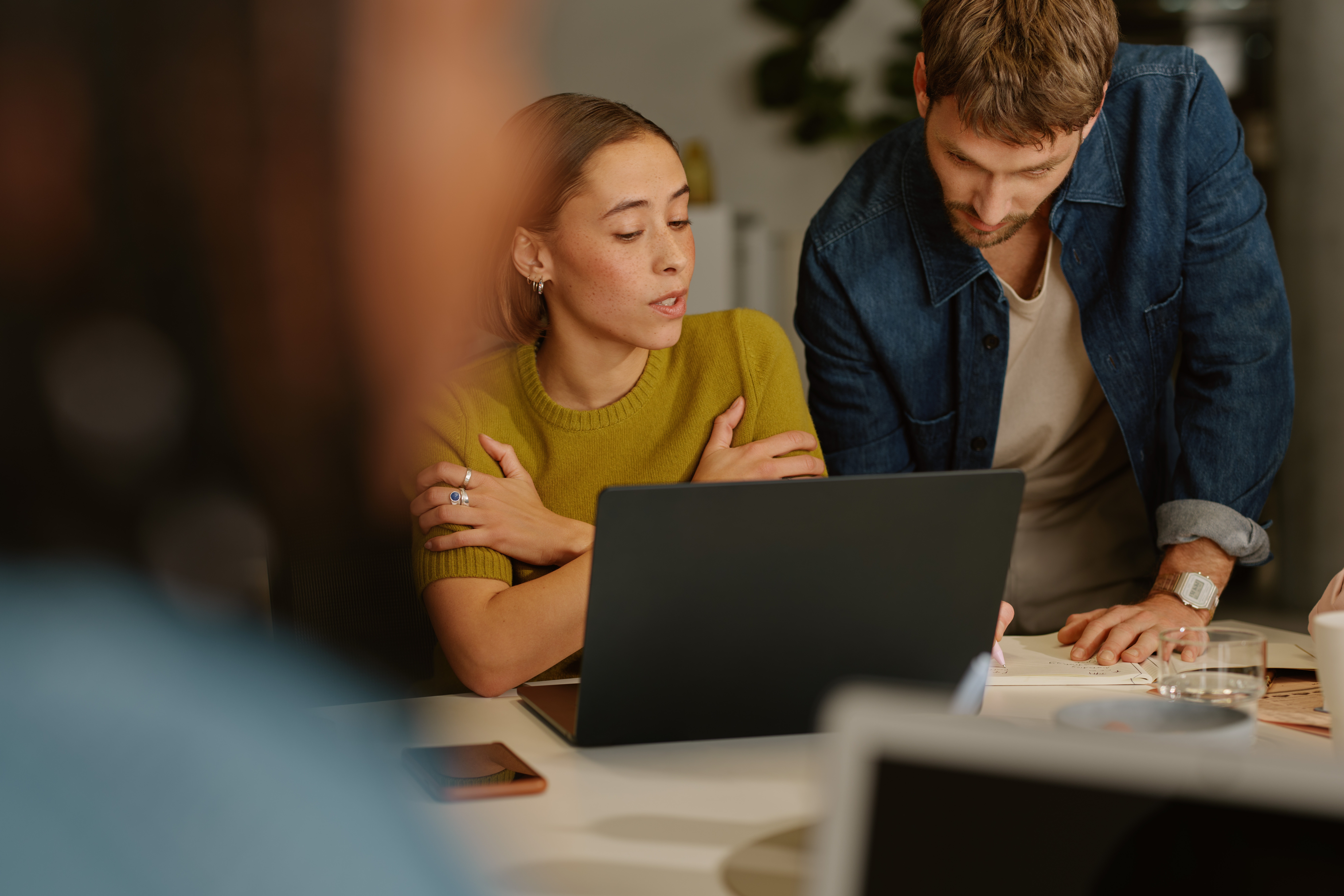 Colleagues discussing their work while looking at the same laptop screen