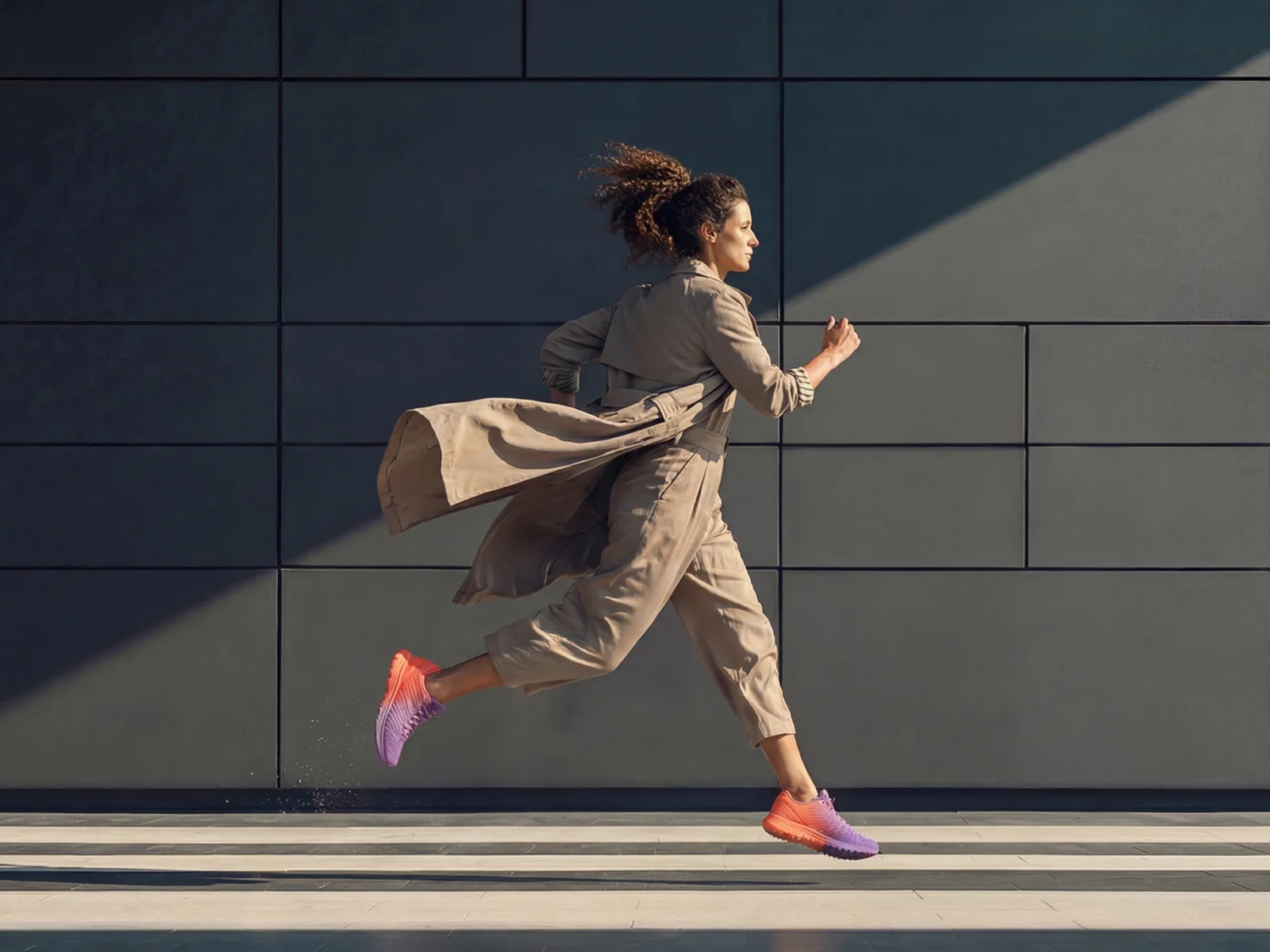 Woman in beige outfit and colorful sneakers sprinting beside a dark wall, next to text reading Die HR Summer Sprints.