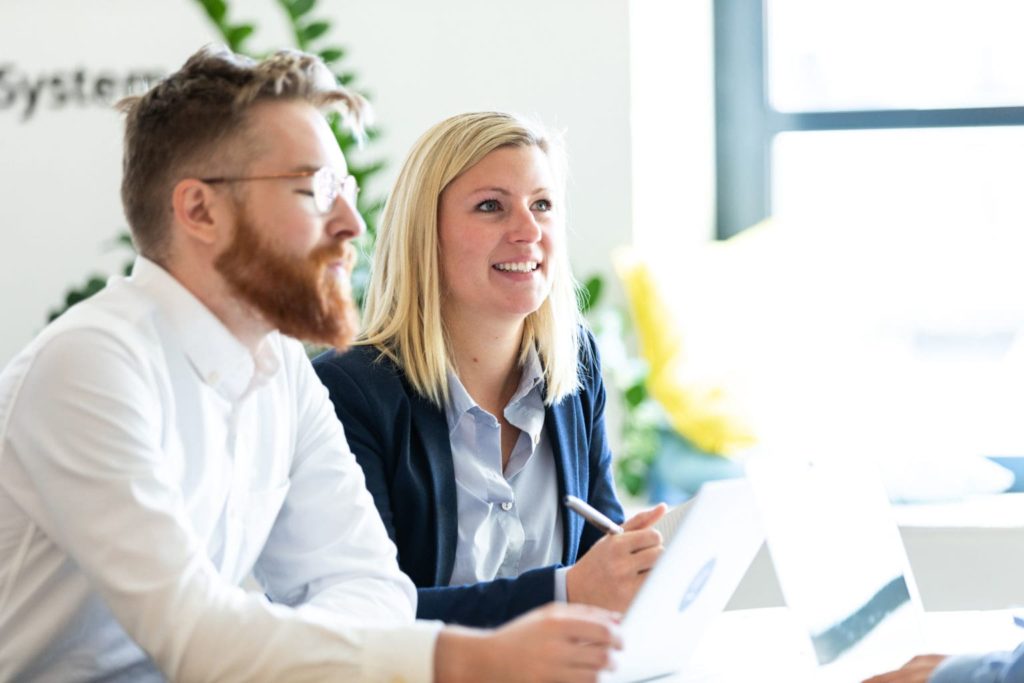 man and woman sitting in front of computer in office