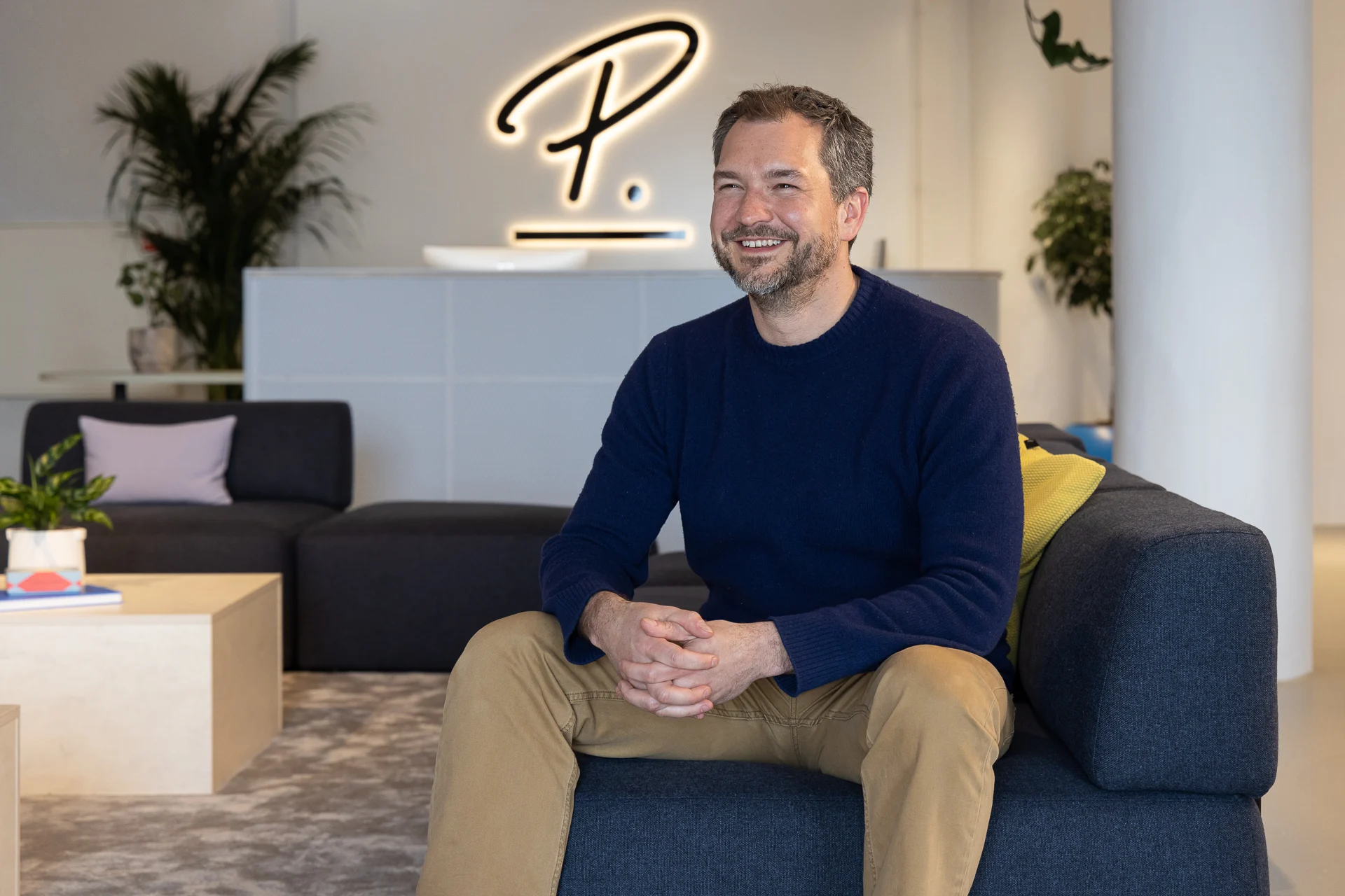 Luke smiling in the Amsterdam office with Personio logo behind him