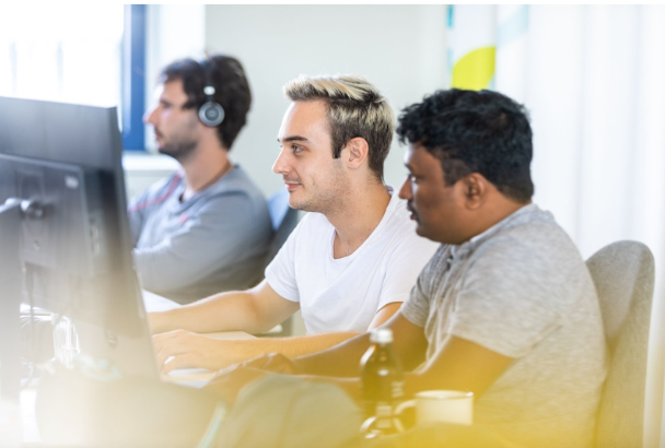 Data teammates sitting at row of desks in front of monitors