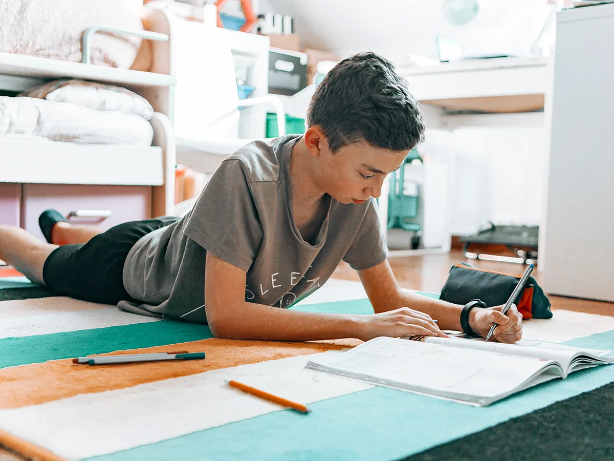 Why kids with ADHD rush through homework, kid laying on the floor doing homework