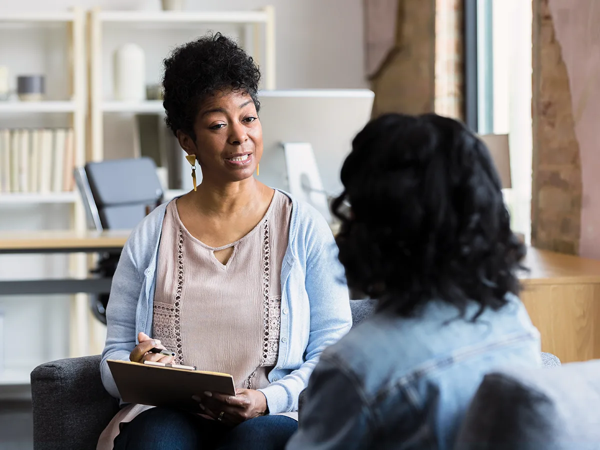 Two adults have a conversation in an office.