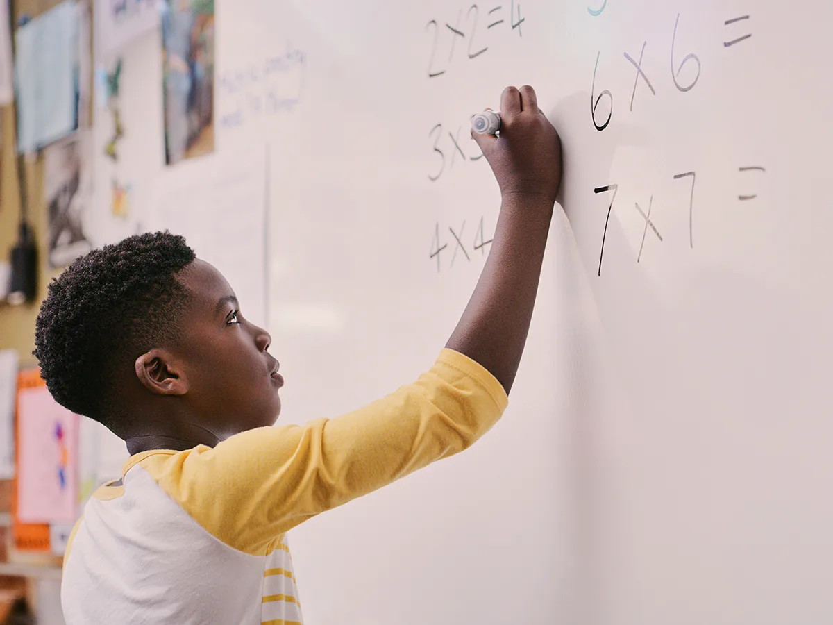 Treatment for kids with dyscalculia, boy writing on a whiteboard 