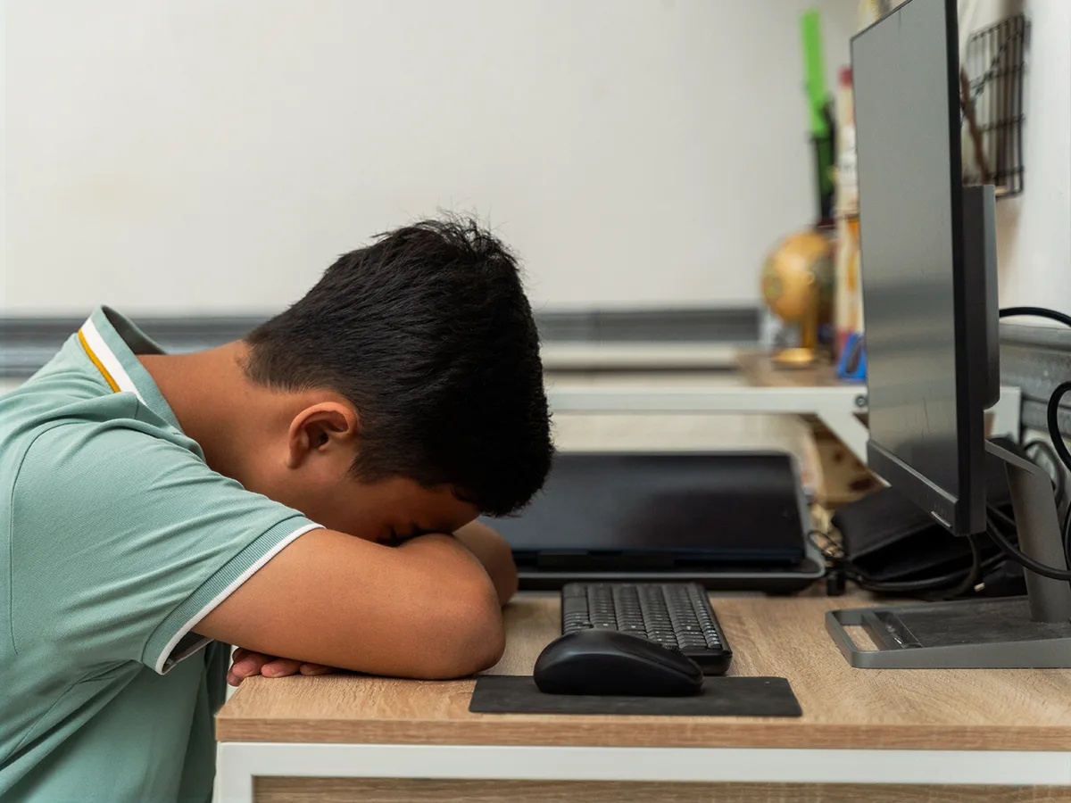 A child laying their head down on a desk. 