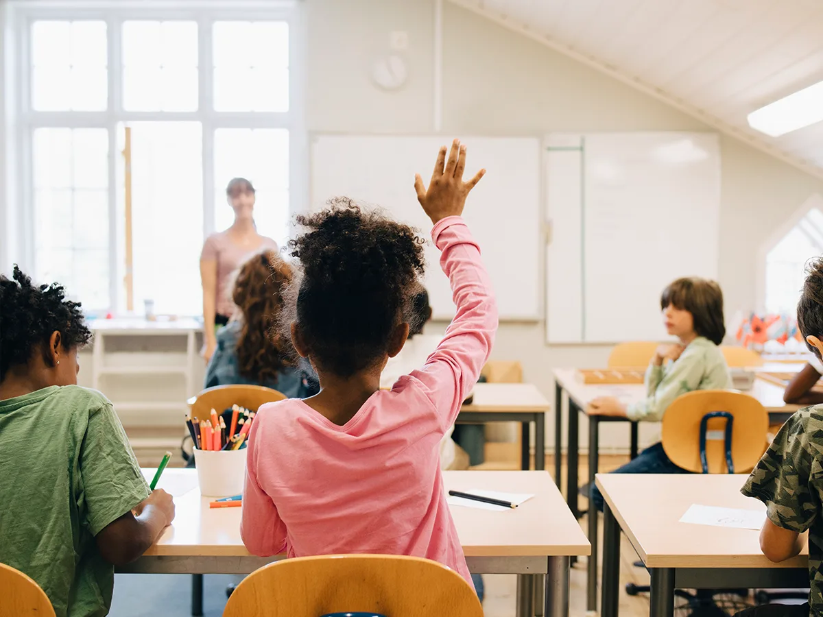6 self-advocacy sentence starters for grade-schoolers with ADHD, girl raising her hand during class