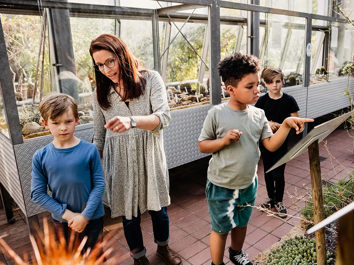 A group of students are in a greenhouse with an adult. 