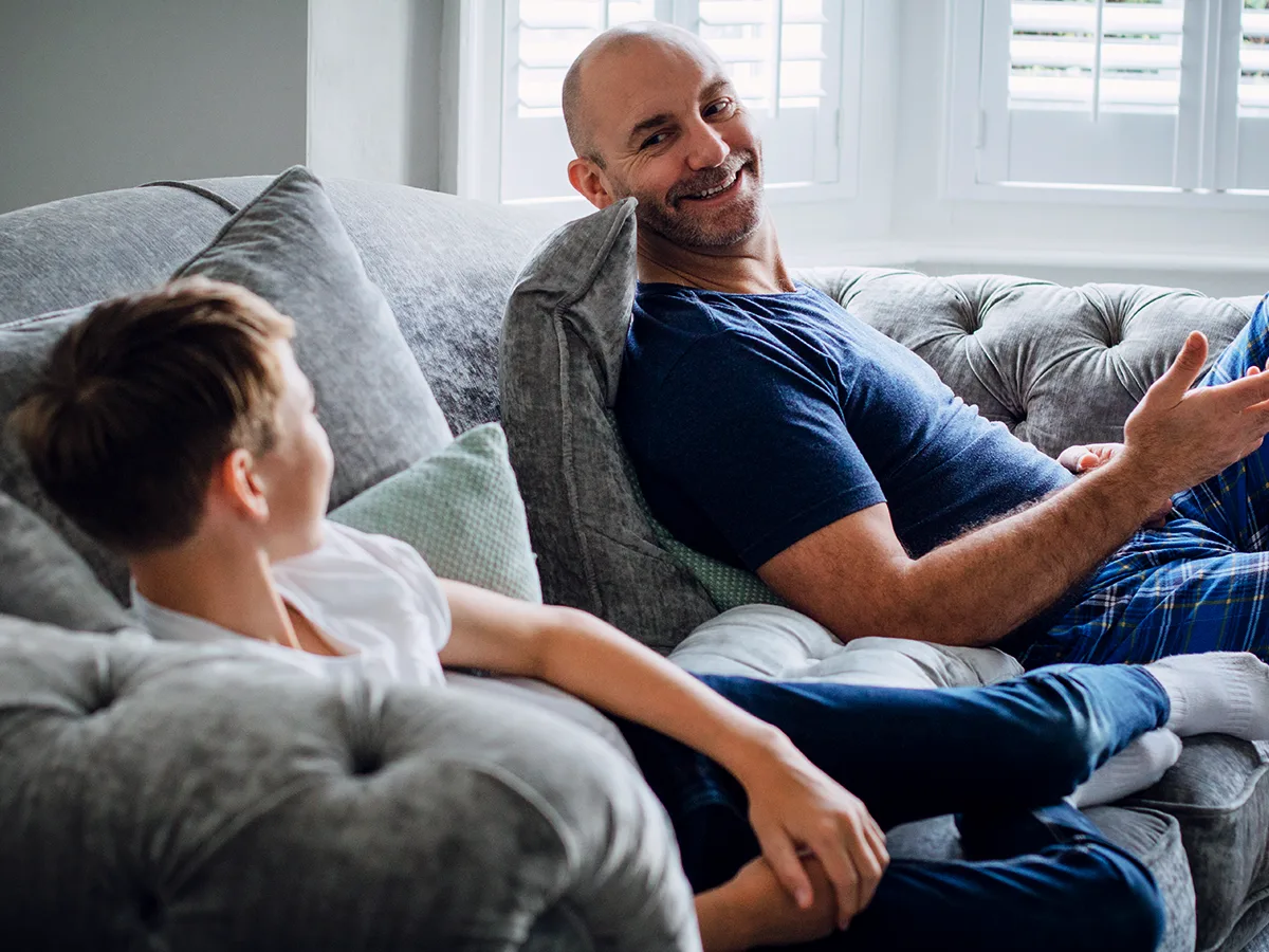 10 ways to improve your middle-schooler’s communication skills. A parent and their tween child have a conversation in their living room while lying on the couch. 