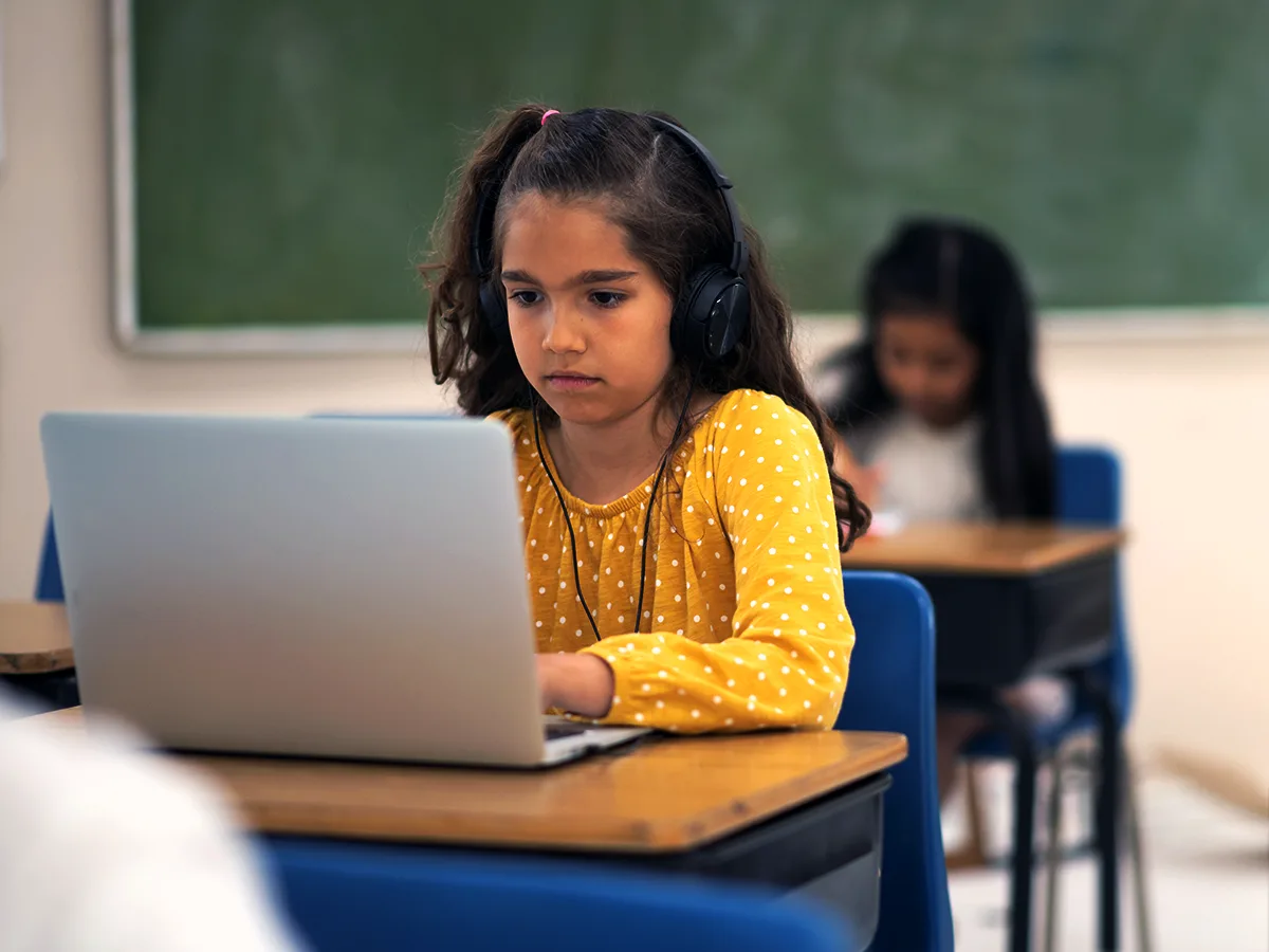 How to get your child help in school without an evaluation. A young student at their desk uses headphones with a laptop. 