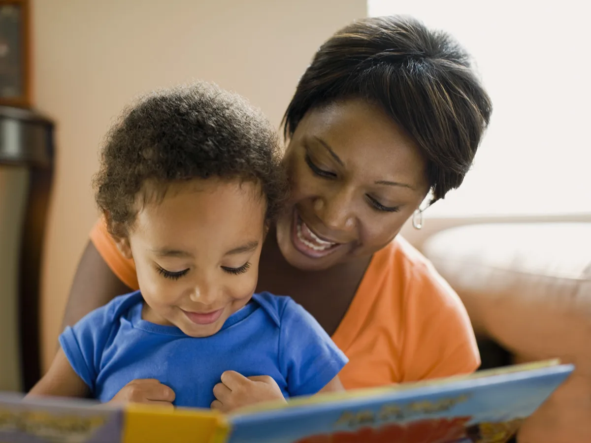 A parent and young child read a book together. 