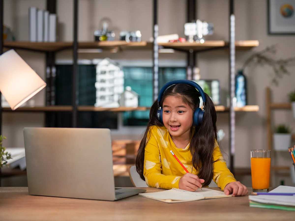 Where to find free audiobooks and digital text-to-speech books for your child, young girl sitting at a desk at home listing to an audio book