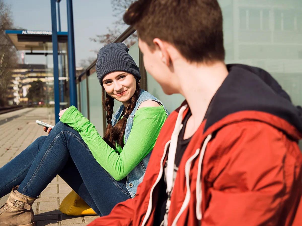 ADHD and falling in love, teen girl and teen boy sitting on the ground looking longingly at one another