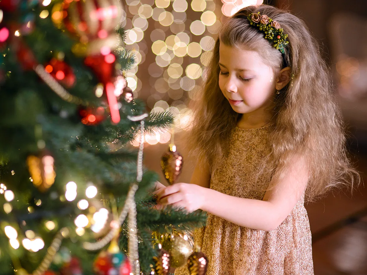8 difficult holiday situations for kids with anxiety, girl playing with an ornament on a tree